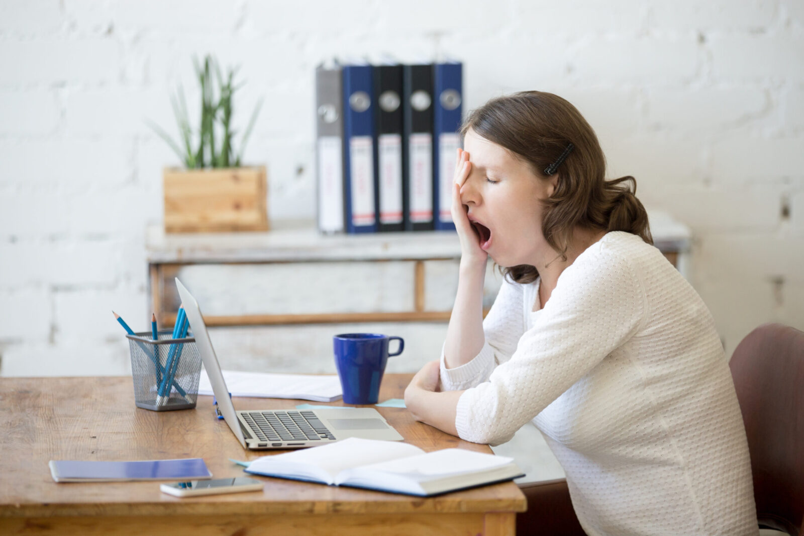 Vrouw is aan het gapen voor haar bureau